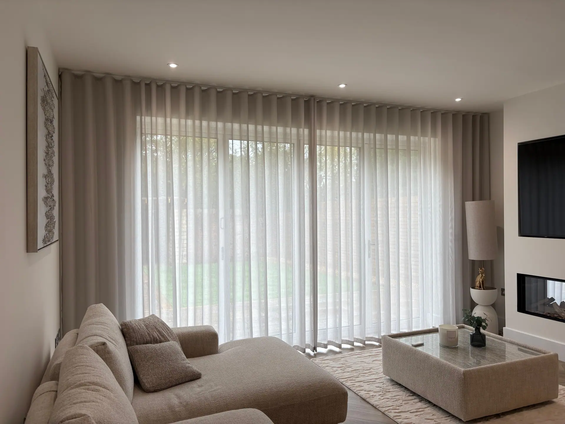 Soft stone wave-heading sheer curtains across wide patio doors in a neutral living room